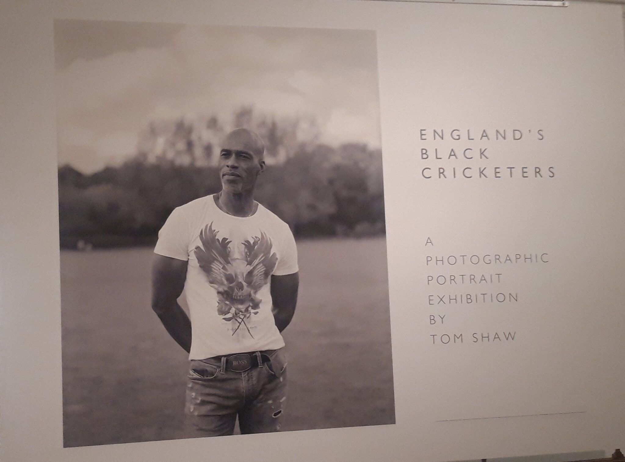 Intro board for the exhibition 'England's Black cricketers' by Tom Shaw. Featuring a black and white photo of Chris Lewis , wearing a white T-shirt standing with his hands behind hi back