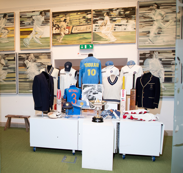Display of India Cricket kit. Stylised cricket paintings on wall behind